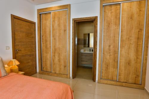a bedroom with wooden doors and a bed and a bathroom at Hanah Apartments by Living Essaouira in Essaouira