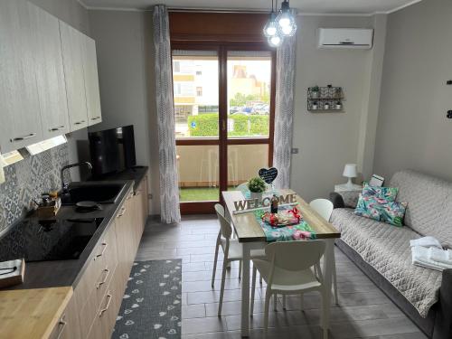 a kitchen and living room with a table and a couch at Casa vacanze “Dolce sosta” in Quartu SantʼElena