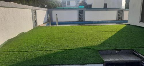 un patio de césped verde al lado de un edificio en Joshi Villa, en Talāsri