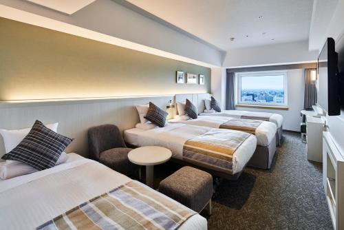 a hotel room with three beds and a window at HOTEL MYSTAYS PREMIER Sapporo Park in Sapporo