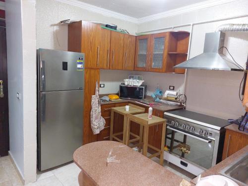 a kitchen with a stainless steel refrigerator and wooden cabinets at شقة بمطار القاهرة in Cairo