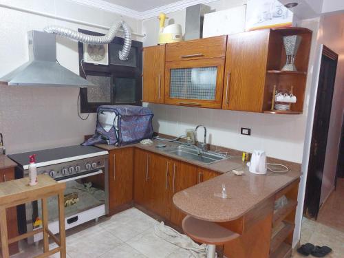 a kitchen with wooden cabinets and a sink and a stove at شقة بمطار القاهرة in Cairo