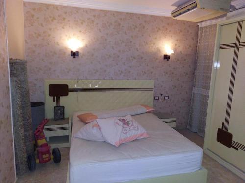 a small bedroom with a white bed and a desk at شقة بمطار القاهرة in Cairo