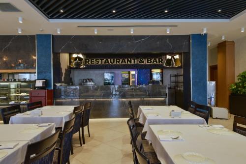 a restaurant with white tables and chairs and a bar at La Flora House Hotel in Kocaeli