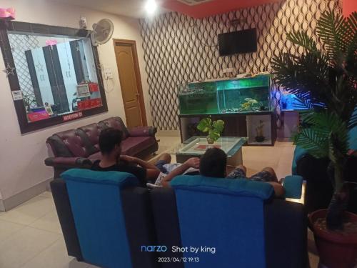 two people sitting on chairs in a living room with a fish tank at Goroomgo Blue Bell Bhubaneswar in Bhubaneshwar