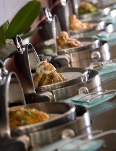 a row of trays filled with food on a table at Hotel Santika Kuta in Kuta