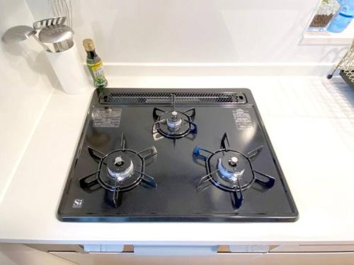 a stove top with three burners on a kitchen counter at 海まで3分！アメリカンビレッジまで5分 最大8名 Moana in Chatan