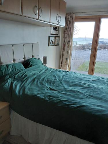 a bedroom with a green bed with a view of the ocean at Ceol Na Mara (Music of the Sea) in Rosemarkie