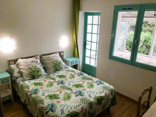 a bedroom with a bed with a comforter and two windows at Hôtel Les Persèdes in Lavilledieu