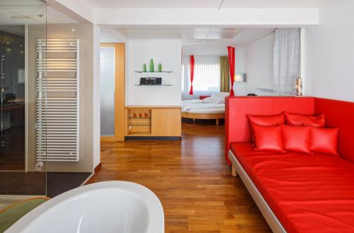 a living room with a red couch and a bedroom at Ramada by Wyndham Baden Hotel du Parc in Baden