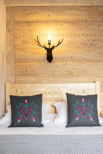 a bedroom with a bed with a headboard and two pillows at Highlander Heart Residence in Zakopane