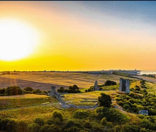 um pôr-do-sol sobre um campo aberto com um monumento de pedra em Cabin de la Paix em Hadleigh