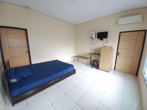 ein Schlafzimmer mit einem blauen Bett und einem Schreibtisch. in der Unterkunft OYO LIFE 93634 Penginapan D'palinggihan Syariah in Cirebon