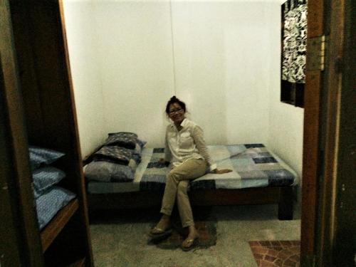 kobieta siedząca na łóżku w pokoju w obiekcie SHALOM CAMP w mieście El Nido