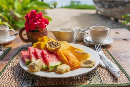 a plate of fruit on a table with cups of coffee at Chunga Changa in Matemwe