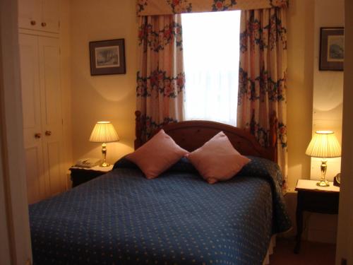 1 dormitorio con cama con almohadas y ventana en Gibtel Lodge & Cafe, en Slough