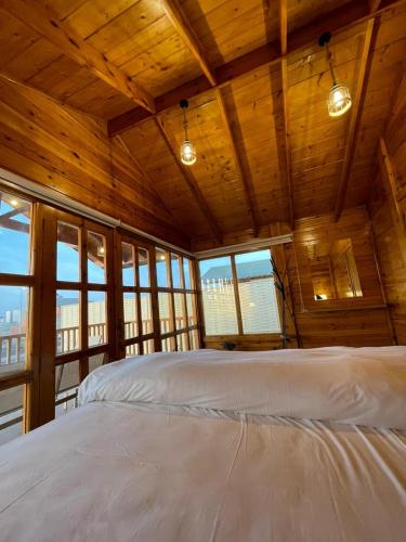 a large bed in a wooden room with windows at اكواخ وشاليهات لوزان الريفية in Dahaban