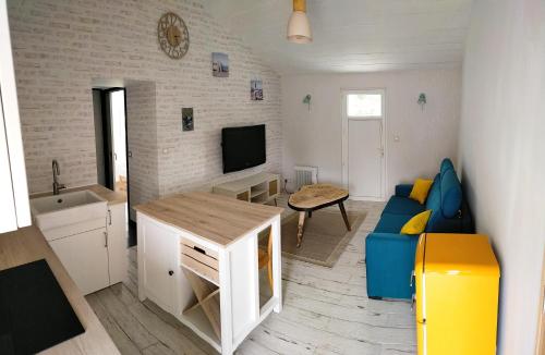 a living room with a blue couch and a television at Le petit logement de la postière in La Garnache