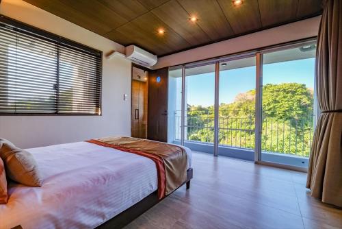 a bedroom with a large bed and large windows at RIVERSIDE TERRACE OKINAWA KADENA in Kadena
