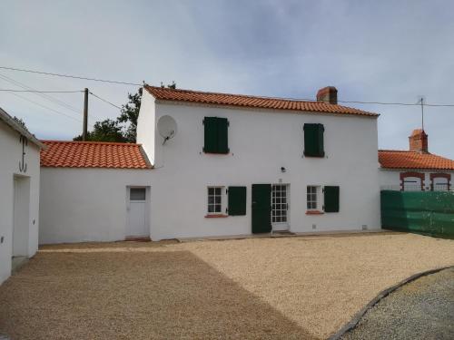 a white house with green shutters and a driveway at Le petit logement de la postière in La Garnache