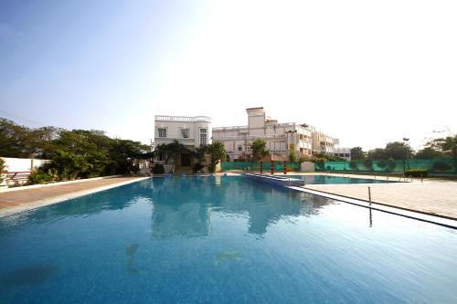 ein großer blauer Pool mit Gebäuden im Hintergrund in der Unterkunft Jenneys Residency in Coimbatore