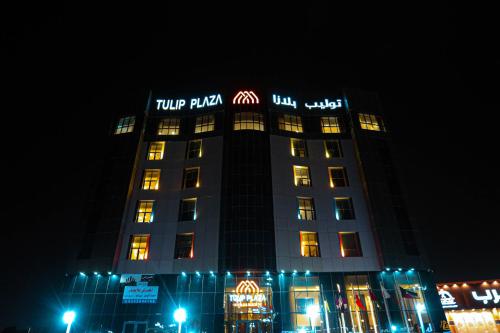 a tall building with lights on it at night at Tulip Plaza By LPC Hotels & Resorts in Hafr Al Baten