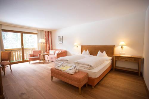um quarto de hotel com uma cama e uma varanda em Parkhotel Tristachersee em Lienz