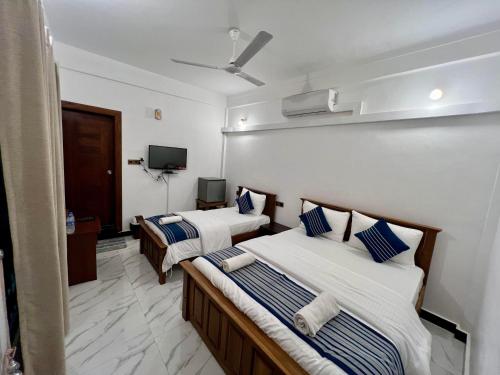 a hotel room with two beds and a flat screen tv at Jaffna Inn in Jaffna