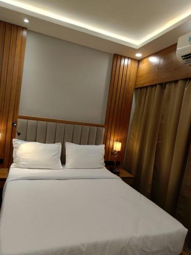 a bedroom with a large bed with white pillows at BANMALI REGENCY in Jamshedpur