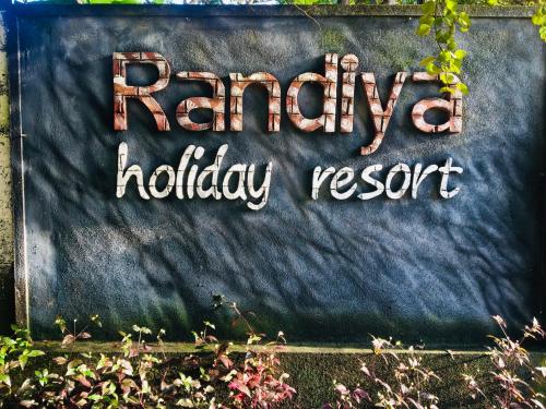 a sign for a happy holiday resort on a wall at Randiya Holiday Resort in Minneriya