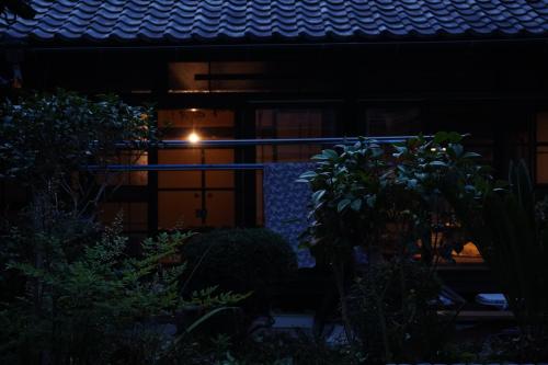 una casa por la noche con una luz en la puerta en ゲストハウス 瀬戸内ライフ en Kure
