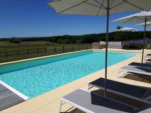 une piscine avec deux chaises et un parasol dans l'établissement La Douce Dordogne, à Coux-et-Bigaroque
