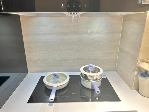 uma cozinha com dois utensílios num fogão com panela em ZHome-Count luxury apartment em Xangai