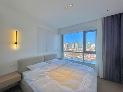 a bedroom with a white bed and a large window at ZHome-Count luxury apartment in Shanghai