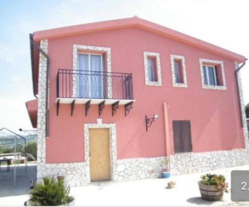 una casa rossa con balcone e porta di Pergole a Realmonte