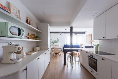 a kitchen with white cabinets and a dining room at Exclusive cozy Atocha apartment in Madrid