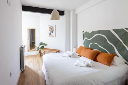 a white bed with orange pillows in a room at Exclusive cozy Atocha apartment in Madrid