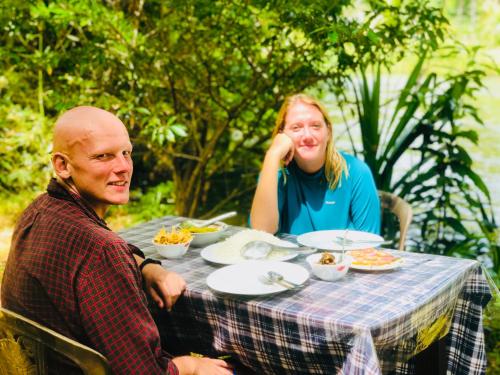 Um homem e uma mulher sentados à mesa com comida. em Randiya Holiday Resort em Minneriya