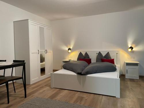 een slaapkamer met een wit bed met rode kussens bij Haus Ribeiro in Schluchsee