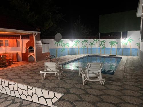 a swimming pool with two chairs next to a house at Miracle Gabala villa in Gabala