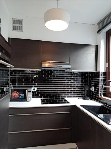una cocina con armarios marrones y una pared de azulejos negros en Appartement confortable au cœur de Brussels, en Bruselas