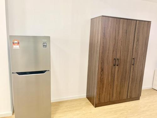 a refrigerator and a wooden cabinet in a room at Deco Home @ Aru Suites in Kota Kinabalu