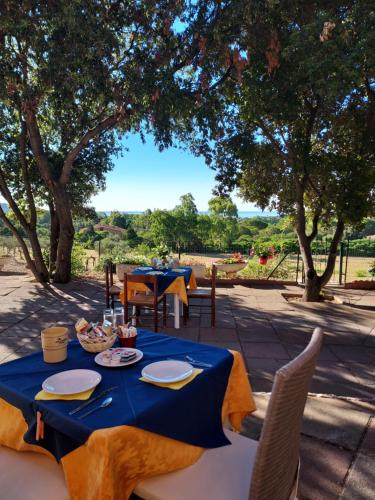 una mesa con un paño de mesa azul, sillas y árboles en La Rosa dei Venti B&B en Chia