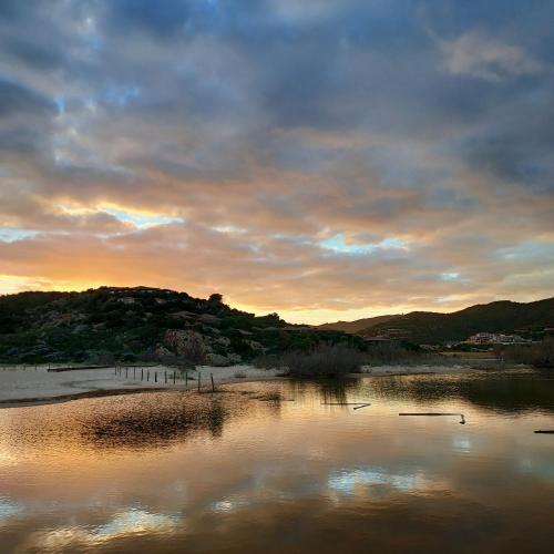 a body of water with a sunset in the background at La Rosa dei Venti B&B in Chia