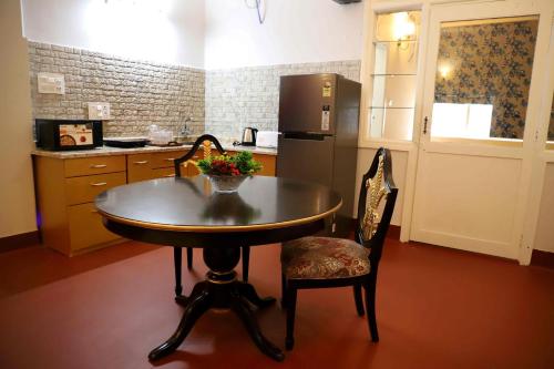 a kitchen with a table and chairs and a refrigerator at Heritage Home in Central Kolkata in Kolkata