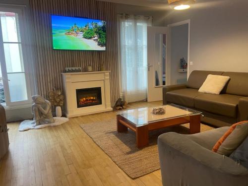a living room with a fireplace and a tv on the wall at Oasis de Détente et Évasion Urbaine au Cœur de la Ville in Colombes