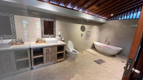 a bathroom with two sinks and a tub and a toilet at Royani Villa in Sukawati