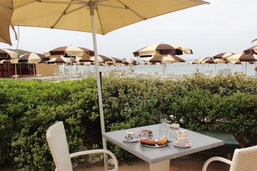 a table and chairs with an umbrella and the beach at Appartamento Lungomare Toscanelli in Lido di Ostia