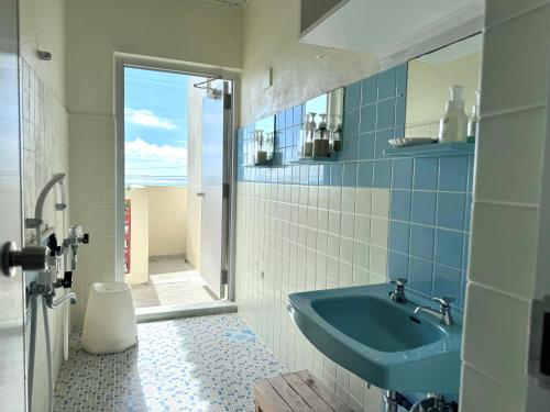 a bathroom with a blue sink and a mirror at ビーチサイドペンションみーばる in Nanjo