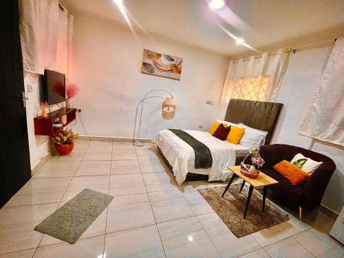 a bedroom with a bed and a couch and a table at Cozy Studio Apartment in Dar es Salaam